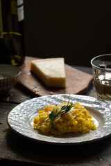 Rustic dinner with risotto all Milanese. Risotto with Saffron and parmesan on white plate on wooden table. 