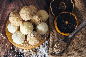 homemade candies wrapped in coconut and nuts, with coconut scattered around and kitchen decorations.