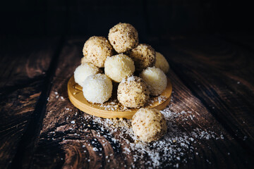 vanilla candies with coconut and walnut sprinkles stored in a tower on a wooden background