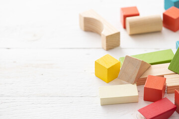 Games with colorful wooden bricks on a white wooden table. The child plays with geometric shapes...