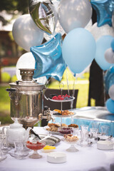 View of a round table with tea-ware from a traditional Russian samovar. Bakery, sweet food concept. Delicious pastries, jam and berries on the table. Birthday celebration. Children's holiday.