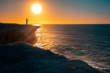 sunset over the sea with fisherman 