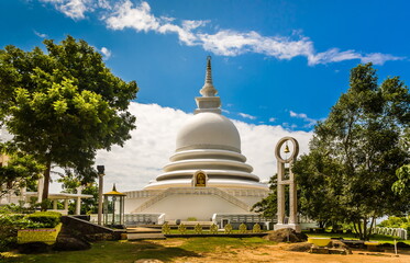 A religious building in Sri Lanka against the background of leafy trees and a blue sky with white clouds