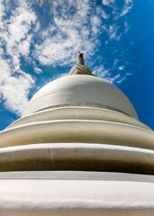 Part of a religious building close-up in Sri Lanka against a blue sky with white clouds