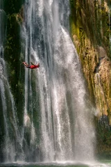 Foto op Canvas Man jumping on Waterfall in deep rain forest jungle Thailand. © Markus