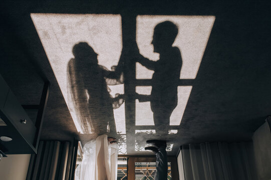 The shade from the sun of the bride and groom near the window on the floor. Wedding portrait, idea.