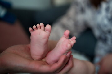 Father's hands holding cute newborn baby feet