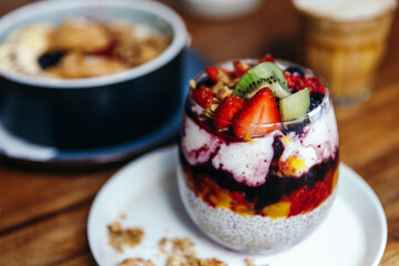 Healthy breakfast with chia strawberry pudding, oatmeal bowl with banana, peanut butter, blackberries, raspberries, nuts, seeds and goji berries