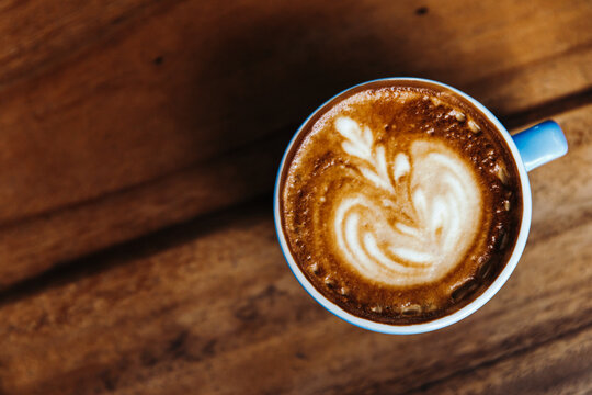 Cappuccino in a blue mug on a wooden table. Coffee view from above.