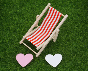 striped deck chair with two heart on a green meadow 