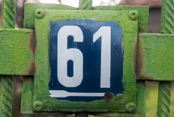 Weathered grunge square metal enameled plate of number of street address with number 61