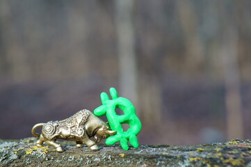 Metal bull and Bitcoin sign close-up.