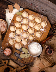 homemade dumplings with meat on rustic wooden board and table with flour, sackcloth
