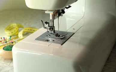 Close-up of a sewing machine. Needle holder with needles, tape measure on the table. Hobby, work at home, home crafts.