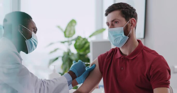 African american doctor servicing male custome rin private clinic hospital doing vaccination injection against flu influenza.
