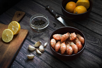 Boiled Greenlandic prawns with spices, garlic and lemon on a wooden background. Preparing a seafood dinner. A quick and healthy dinner.Rustic style