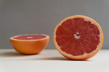 Slicing fresh organic pink grapefruit on a gray background close-up. Eating grapefruit reduces cholesterol levels in the blood and promotes weight loss. Dietary nutrition. Minimalist composition