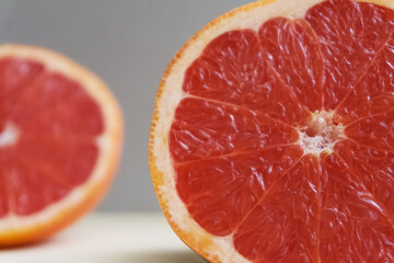 Slicing fresh organic pink grapefruit on a gray background close-up. Eating grapefruit reduces cholesterol levels in the blood and promotes weight loss. Dietary nutrition. Texture