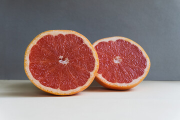 Slicing fresh organic pink grapefruit on a gray background close-up. Eating grapefruit reduces cholesterol levels in the blood and promotes weight loss. Dietary nutrition. Minimalist composition.