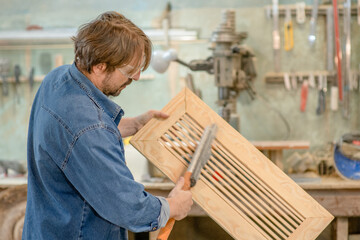 Fototapeta na wymiar Carpenter makes a wooden part in a workshop