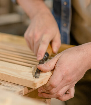 Close up hands of carpenter with chisel in the hands on the workbench in carpentry