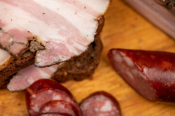 Sandwich with smoked brisket sliced on grain bread and homemade sausage on a wooden cutting board.