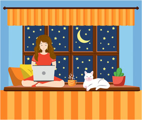 A woman works at a laptop while sitting on the windowsill at home. Freelance concept, quarantine due to covid-19.