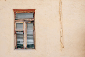 Fototapeta na wymiar Wooden window of the old building on the background of the wall