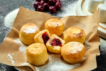 Homemade Ukrainian cheesecakes with fruit filling on craft paper on a dark background. Close up view on Syrniki, selective focus