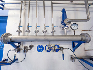 Natural gas pipes with ball valves and fittings on the wall. The warning board with safety instructions