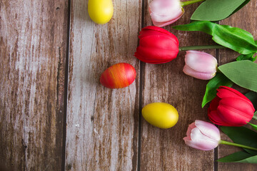 Pink and red tulips and Easter eggs on a brown wooden background. Spring background. Background for design.  Easter. Copy space.