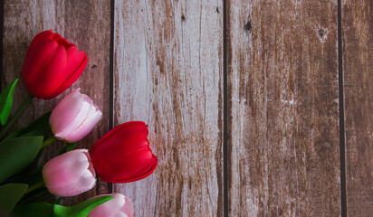 Bouquet of pink and red tulips on a brown wooden background. Background for design. Spring background. Mother's Day. Women's Day. Spring day. Easter. Copy space.