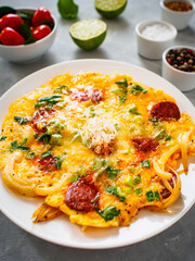 Delicious breakfast - scrambled eggs with onion, parmesan and chorizo on wooden table
