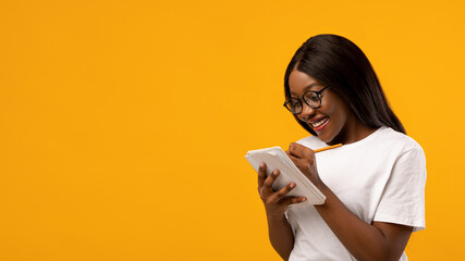Excited black woman making plans over yellow background