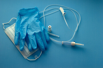 Medical consumables, syringes, gloves, needles on a blue background. 