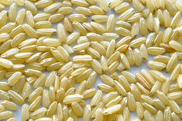 The seeds of unrefined rice lie on a white table.