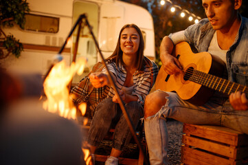 Obraz na płótnie Canvas Friends playing on guitar by the bonfire, camping