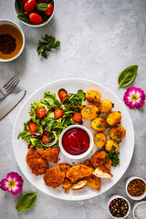 Fried breaded chicken nuggets with fried potatoes  and fresh vegetables
