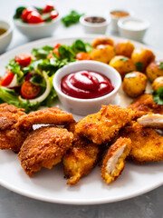 Fried breaded chicken nuggets with fried potatoes  and fresh vegetables
