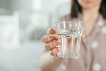Young woman holding glass with water in hands. Self care concept. Formation of healthy useful habit