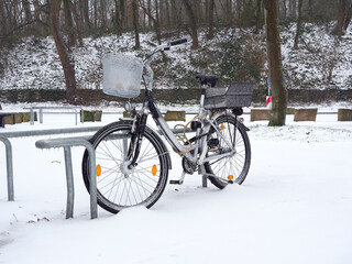 Snow-covered and ice-covered bicycle strapped to a bicycle rack. Difficult winter weather...