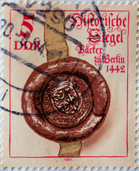 GERMANY, DDR - CIRCA 1984 : a postage stamp from Germany, GDR showing a historical seal with ribbon: seal of the bakers of Berlin (1442)