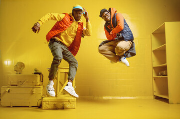 Two stylish rappers in studio, yellow background