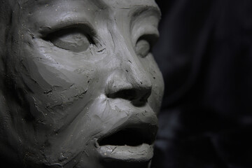 Sculpture of asian woman, wet clay, face detail , on black background
