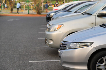 Closeup of front side of bronze car with other cars parking in outdoor parking area in twilight evening. 