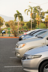 Closeup of front side of bronze car with other cars parking in outdoor parking area in the evening. Vertical view.