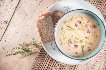 Delicious mushroom cream soup with champignons on the wooden table
