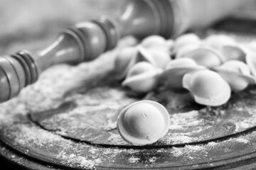 Traditional pelmeni or dumpling at cutting board. Homemade preparation food. Black and white.