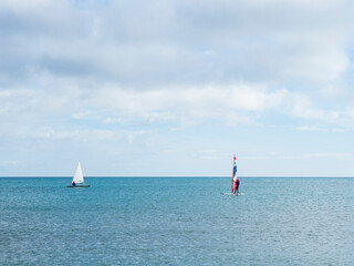 Fototapeta premium Barco de vela y deportista con windsurf en un mar tranquilo de invierno
