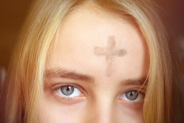 Girl with cross made from ash on forehead. Ash wednesday concept.